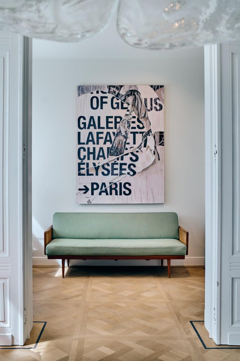 Eiken visgraat parketvloer in een licht designinterieur met groene sofa en groot abstract kunstwerk aan de muur